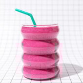pink smoothie with green straw on black and white tiles