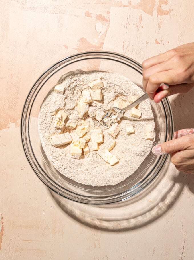 hand blending butter cubes into flour