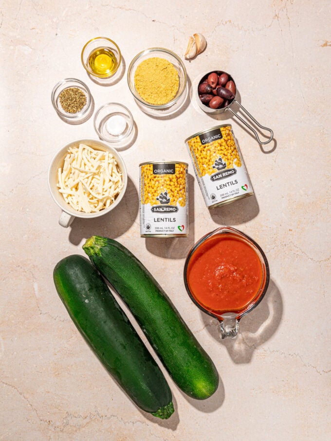 canned lentils, zucchinis, bowls of cheese shreds, olives and marinara